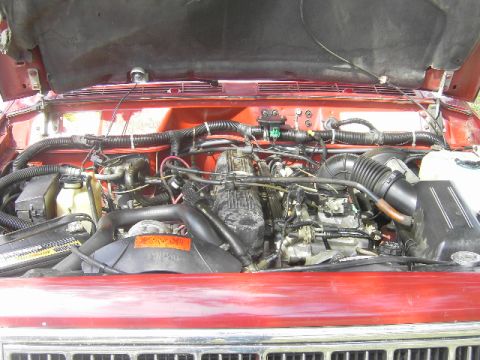1991 Jeep Cherokee - The engine bay of a red Jeep Cherokee is visible with the hood raised.