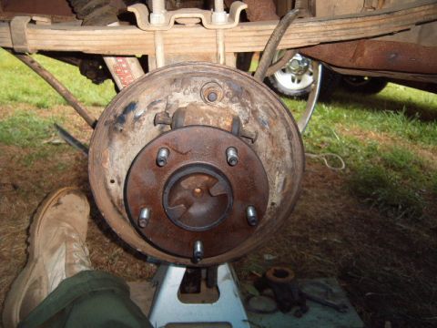 1988 Ford Bronco - Close-up view of a vehicle's rear drum brake assembly, supported by jack stands.