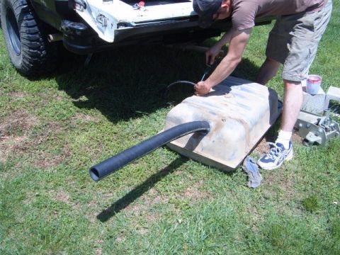 1988 Ford Bronco - A man works on the fuel tank of a 1988 Ford Bronco, seen from the rear.