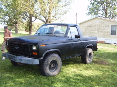 1988 Ford Bronco - This black Ford Bronco has a custom bumper and off-road tires. A website sticker is visible on the windshield.