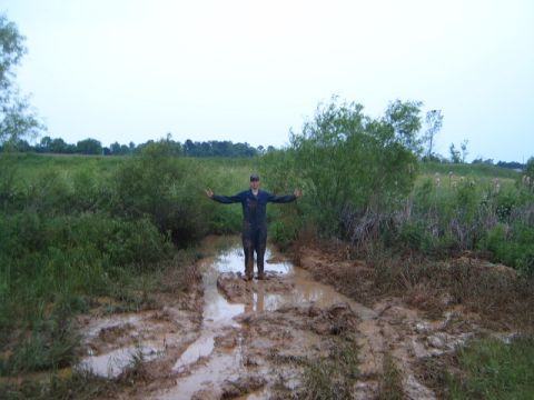1988 Ford Bronco - A person stands in a muddy path surrounded by vegetation, with arms spread wide.