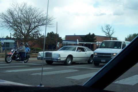 1972 Ford Ranchero - A white Lincoln Continental Mark V and a Siemens van are stopped at a crosswalk with a motorcycle in the background.