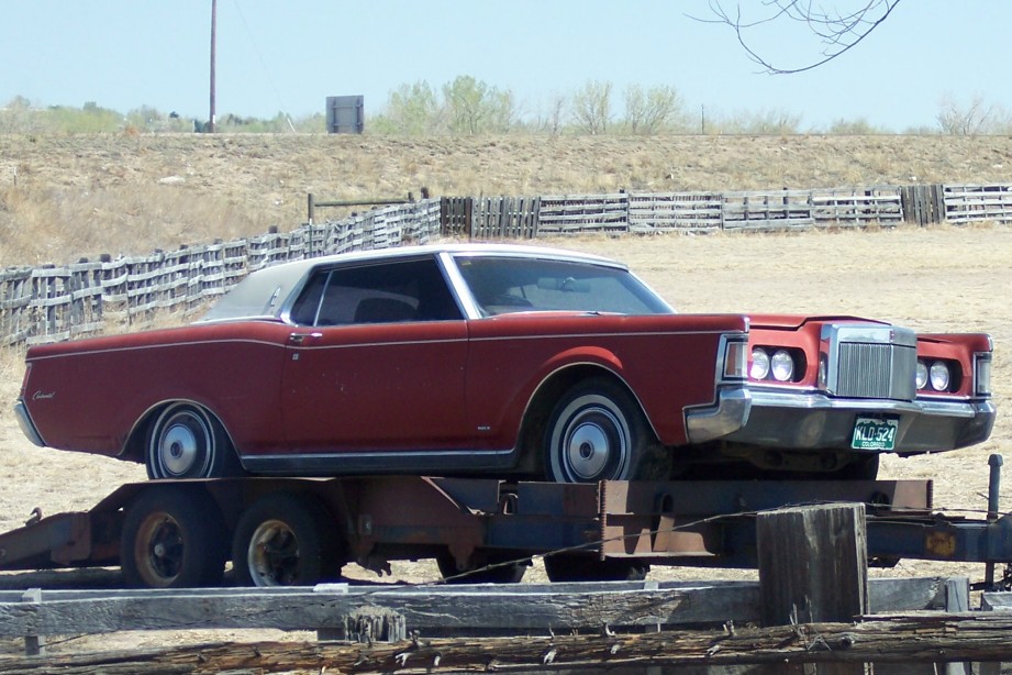 Red coupe with a white vinyl roof on a trailer, front view