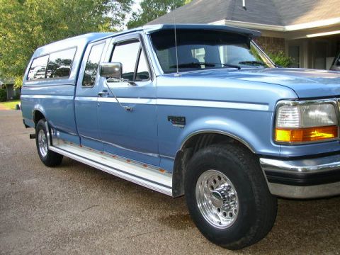 1995 Ford Bronco - This blue pickup truck, likely a 1992 Ford F-250, is shown from a 3/4 front angle.
