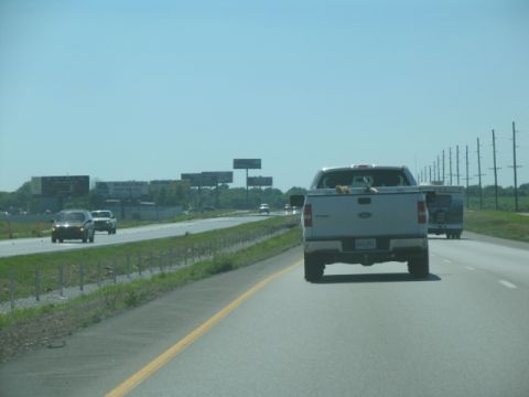 1988 Ford E250 - A silver pickup truck drives down a highway with a trailer following closely behind.