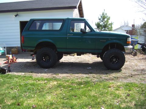 1996 Ford Bronco - A green 1996 Ford Bronco with a significant lift kit and off-road tires is shown from the side.