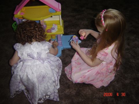 1993 Ford Bronco - Two young girls are engaged in play with a colorful dollhouse and miniature figures on a dark carpet.