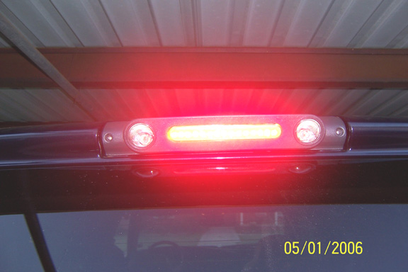 Illuminated red third brake light bar with cargo lamps above a vehicle's rear glass