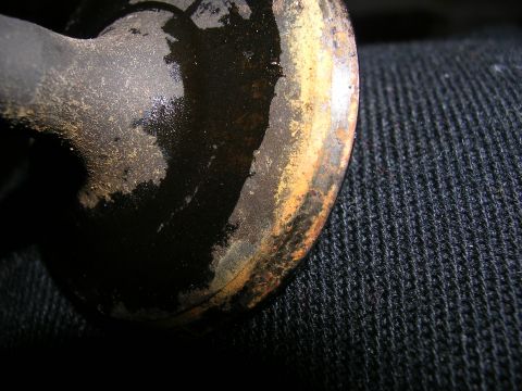 1996 Ford Probe - A close-up view of a worn and corroded metal part, possibly from a vehicle, resting on dark fabric.