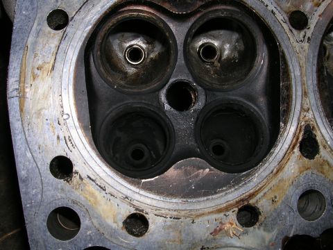 1996 Ford Probe - This is a close-up view of a used engine cylinder head, revealing significant carbon deposits around the valve seats.