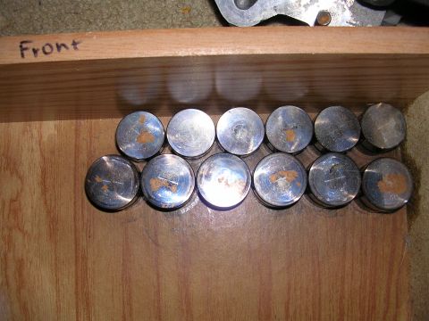 1996 Ford Probe - Twelve valve tappets are laid out on a wooden surface, with the word 'Front' visible on a plank above.