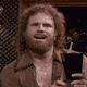 1977 Ford F-150 - A man with a beard and long, curly hair holds a drink while looking off to the side.