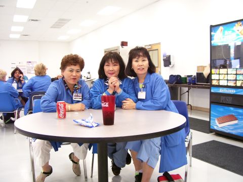 1994 Ford Probe - Three women in blue lab coats sit at a table with drinks, with a vending machine visible in the background.