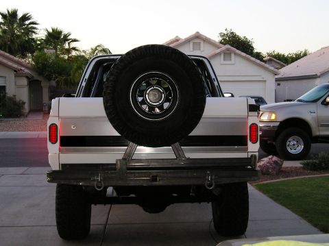1993 Ford Bronco - The rear of a white SUV is shown with a spare tire mounted externally. A second vehicle is visible to the right.