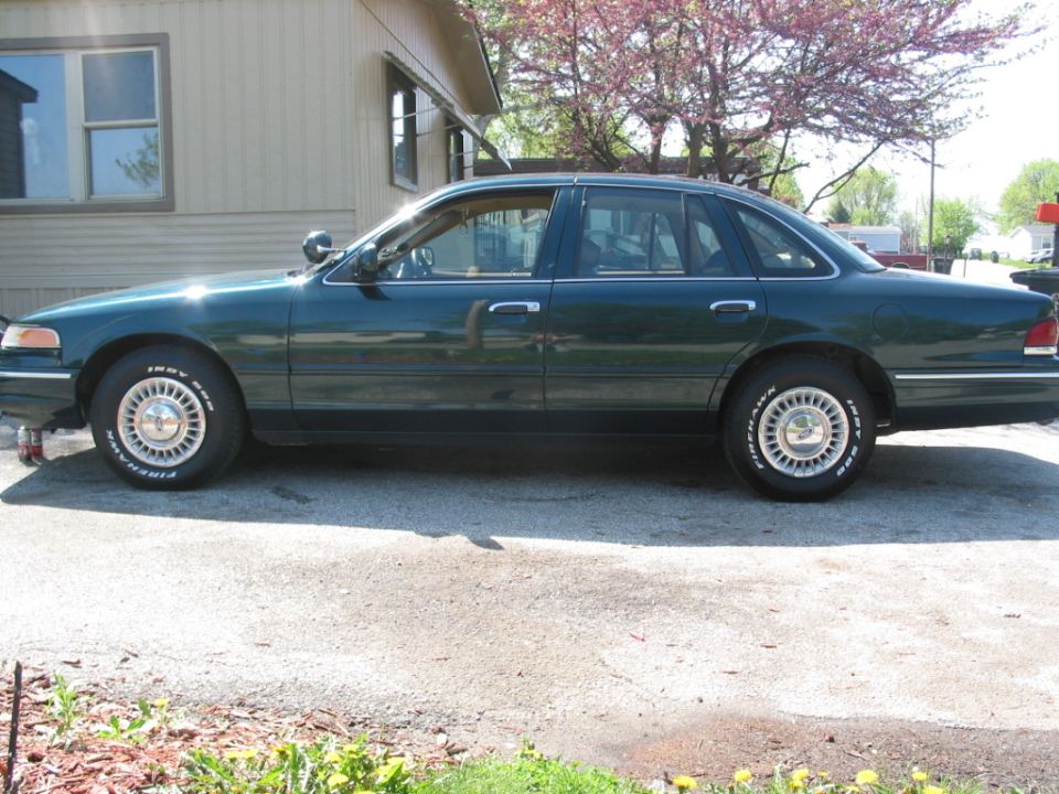 Dark green 1996 Ford Crown Victoria sedan, side view, with chrome trim and wire wheel covers