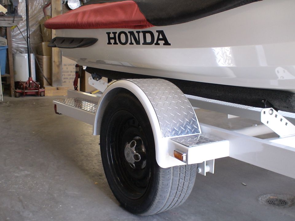 White Honda jet ski on white trailer with diamond-plate fender in a garage