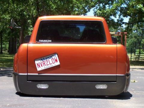 1983 Ford Bronco - Rear view of a lowered orange pickup truck with a custom license plate.
