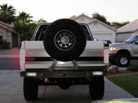 1983 Ford Bronco - Rear view of a white 1983 Ford Bronco, a spare tire mounted on the tailgate and a custom bumper.