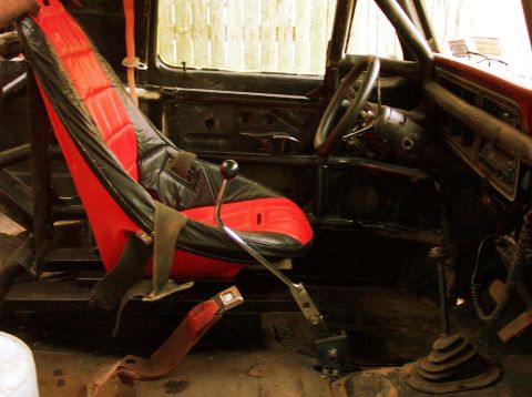 1978 Ford Bronco - The interior of a vehicle modified for off-road racing, a racing seat and roll cage.