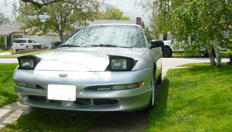 Silver Ford Probe front view with pop-up headlights raised, parked on a lawn