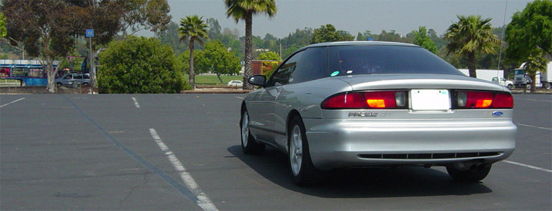 Silver Ford Probe GT rear 3/4 view in an empty palm-lined parking lot