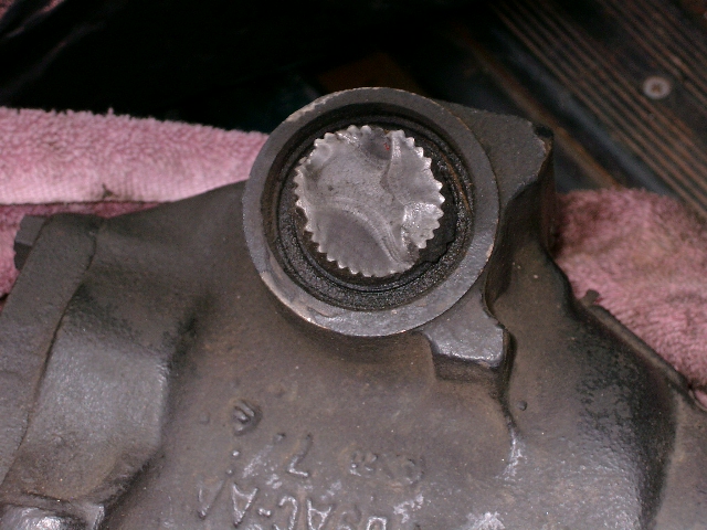 Close-up of a damaged splined shaft within a dark metal housing, with visible part numbers