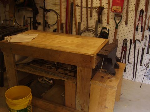 1990 Ford Bronco - A workbench with an anvil and various tools displayed on a pegboard wall in a shop setting.