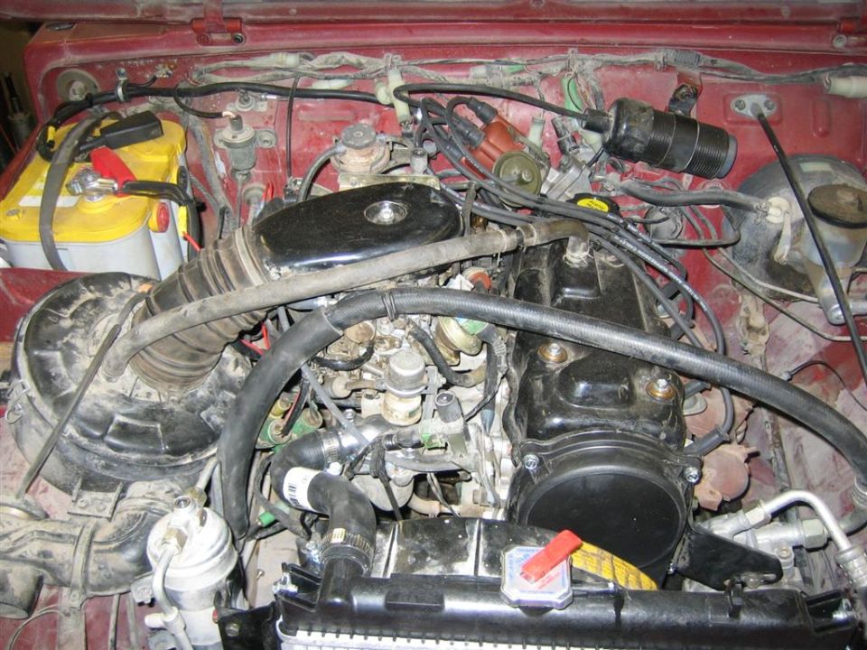 Engine bay with battery, air intake, distributor, and engine block visible