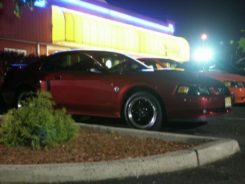 2001 Mercury Grand Marquis - A red coupe is parked in front of a building with neon lights.