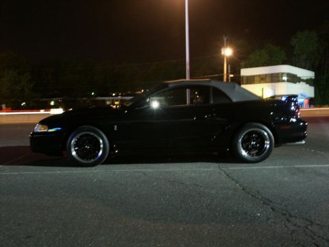 2001 Mercury Grand Marquis - A black convertible sports car is parked at night, showing its side profile.