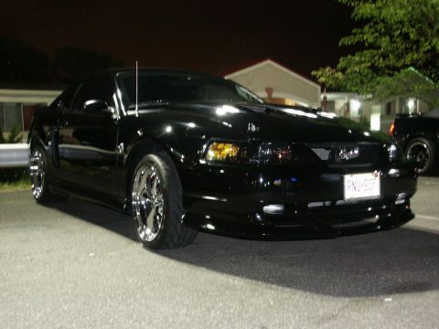 2001 Mercury Grand Marquis - A black Ford Mustang is parked at night, showing its front three-quarter view with custom wheels.