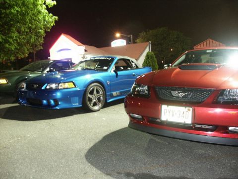 2001 Mercury Grand Marquis - Three Ford Mustangs are parked together at night, with the red one closest to the camera.