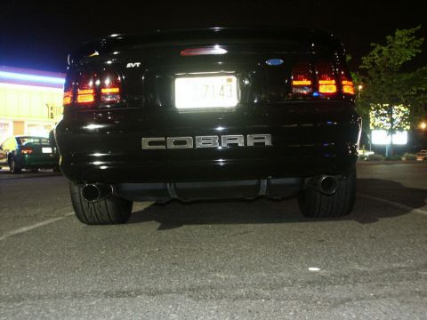 2001 Mercury Grand Marquis - Rear view of a black Ford Mustang Cobra with SVT badging and dual exhaust pipes visible.