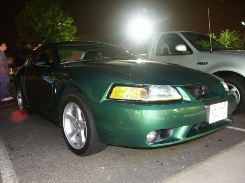 2001 Mercury Grand Marquis - A green Ford Mustang is parked next to a silver pickup truck at night.