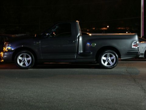 2001 Mercury Grand Marquis - A dark gray Ford F-150 SVT Lightning pickup truck is seen from the side at night.