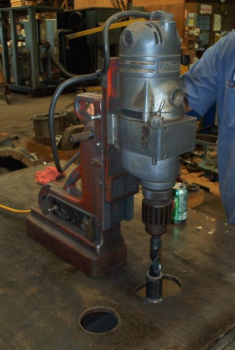 1983 Ford Bronco - A drill press is shown in operation, creating a hole in a workbench. A beverage can sits on the surface.