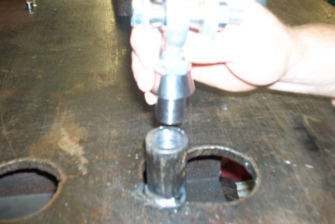 1983 Ford Bronco - A metal trac bar component is being installed into a housing, with a hand guiding the part.