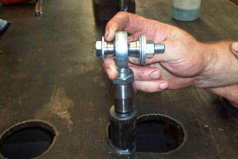1983 Ford Bronco - A close-up shows a person holding a metal rod end, a component of a vehicle's suspension system.