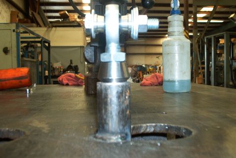 1983 Ford Bronco - Close-up of a metal assembly with bolts and a conical piece, set against a workshop background.