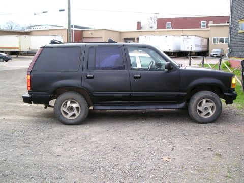 1991 Ford Explorer - Side profile of a matte black 1991 Ford Explorer parked outdoors on a gravel surface.