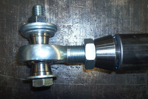 1983 Ford Bronco - A close-up view of a metal trac bar heim joint assembly with threaded rod and fasteners.