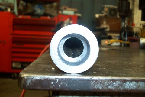 1983 Ford Bronco - A close-up view of a metal tube's end, likely a vehicle part, in a workshop setting.