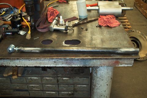 1983 Ford Bronco - A metal rod with an adjustable joint rests on a workbench alongside various tools and shop supplies.