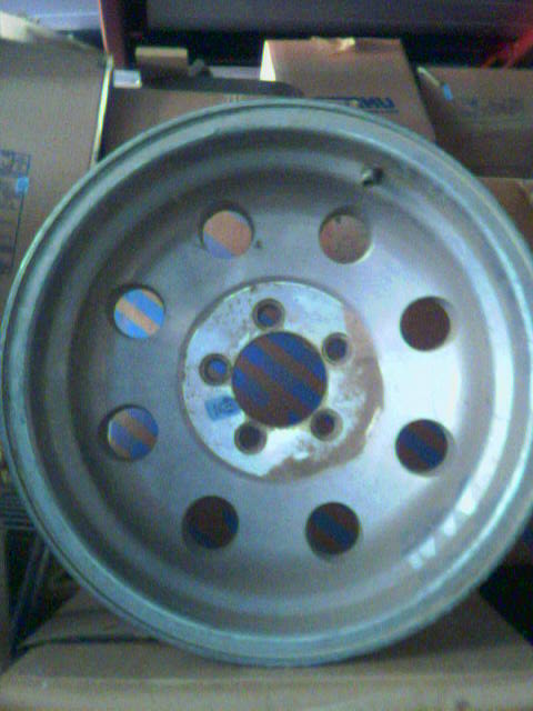 1989 Ford Bronco - A single silver wheel with a multi-hole design and a striped center cap is shown.