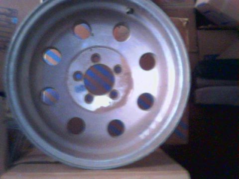 1989 Ford Bronco - A single silver wheel with a distinctive pattern of circular holes and colored accents is shown in detail.