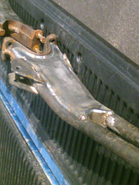 1989 Ford Bronco - A close-up view of a welded metal component, possibly a suspension part, resting in a truck bed.