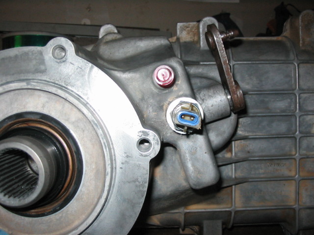 Aluminum transfer case with red plug and blue electrical sensor connector