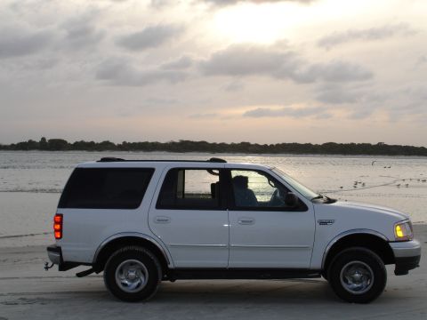 1989 Ford Bronco - A white Ford Expedition is parked on the beach at sunset.
