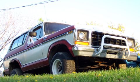 1979 Ford F-250 - A vintage Ford Bronco sits on a grassy lawn under a bright sky, its front end angled towards the camera.