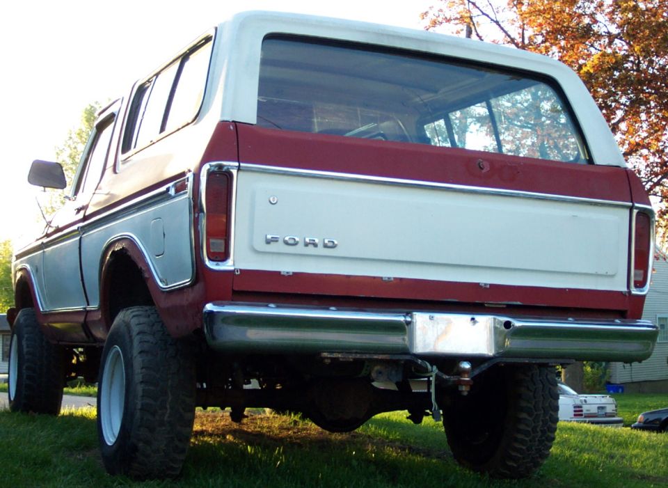 Rear view of a red and white 1978 Ford Bronco with large tires